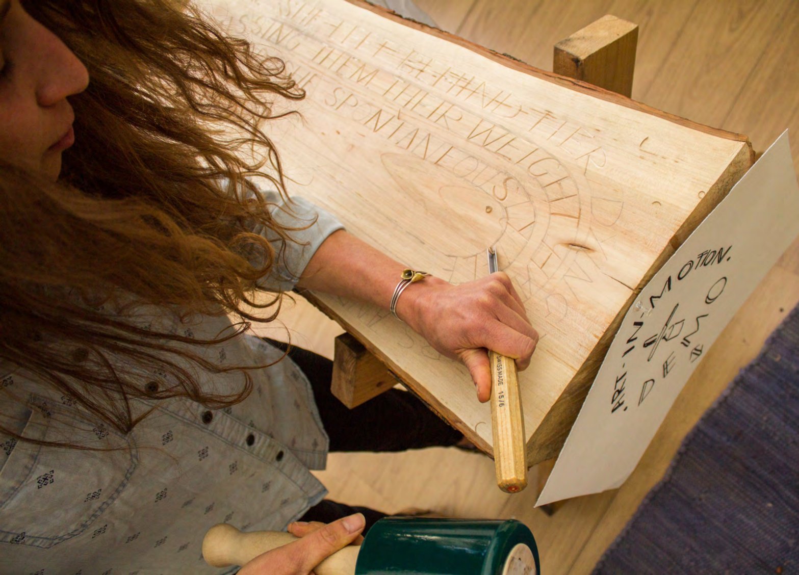 Julie Renee Benda carving lettering into a wooden board