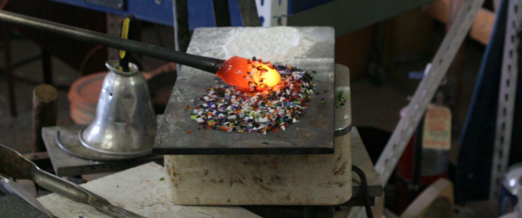 Molten glass being rolled in colored glass frit