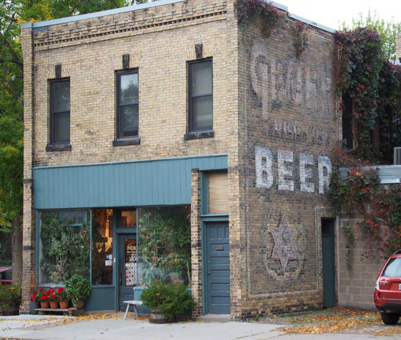 Two-story brick storefront with a faded painted beer advertisement on its side wall