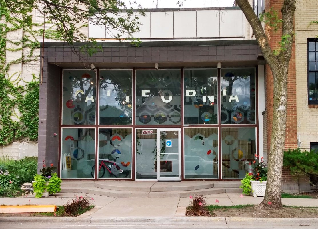 Storefront at 2205 with large windows featuring the word CALIFORNIA in white letters and colorful geometric decals.