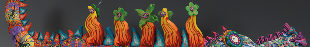 A long, stylized sculpture of a creature with a patterned, colorful body, decorated with flame-like spikes and flower shapes along its back.