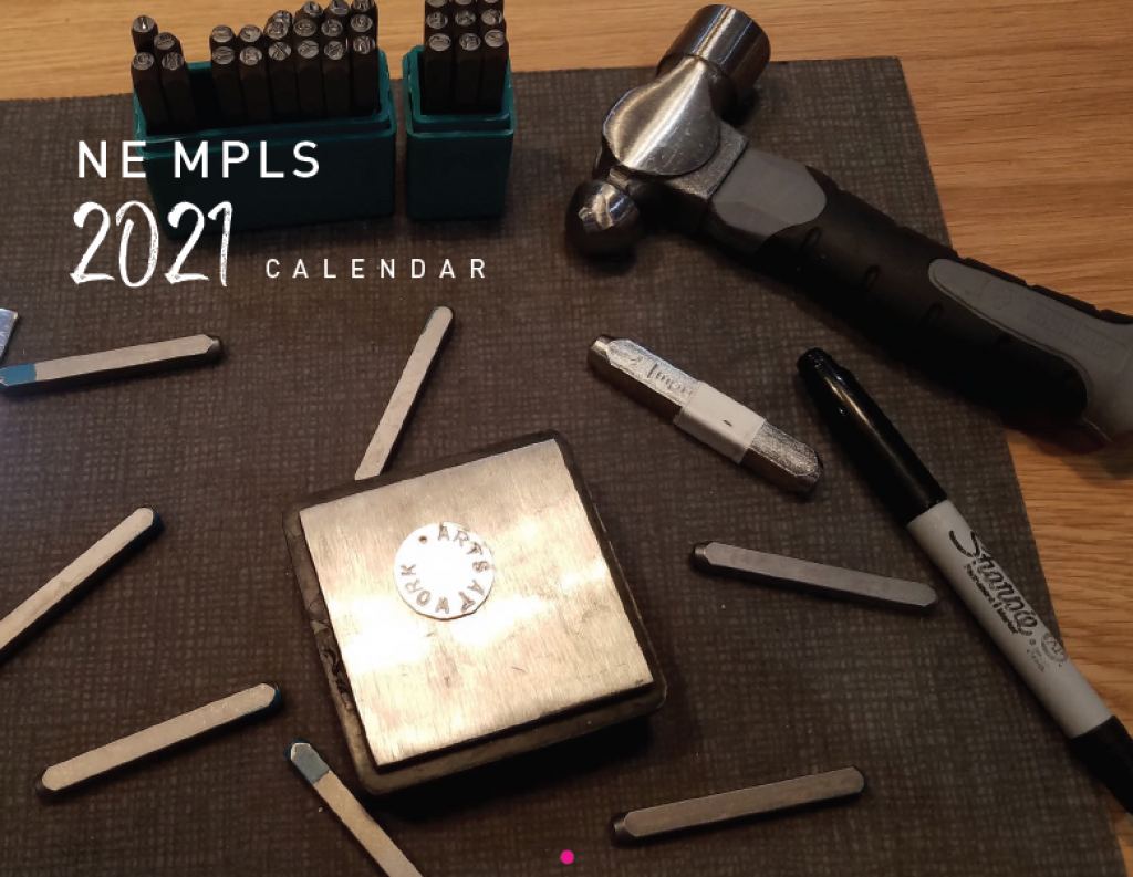 Metal stamping tools, a hammer, and a marker arranged around a square metal block with a stamped circular coin, with text overlay reading NE MPLS 2021 CALENDAR.