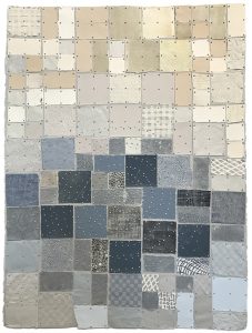 An abstract grid of square fabric patches in shades of white, cream, and various blues, all attached with small metal studs.