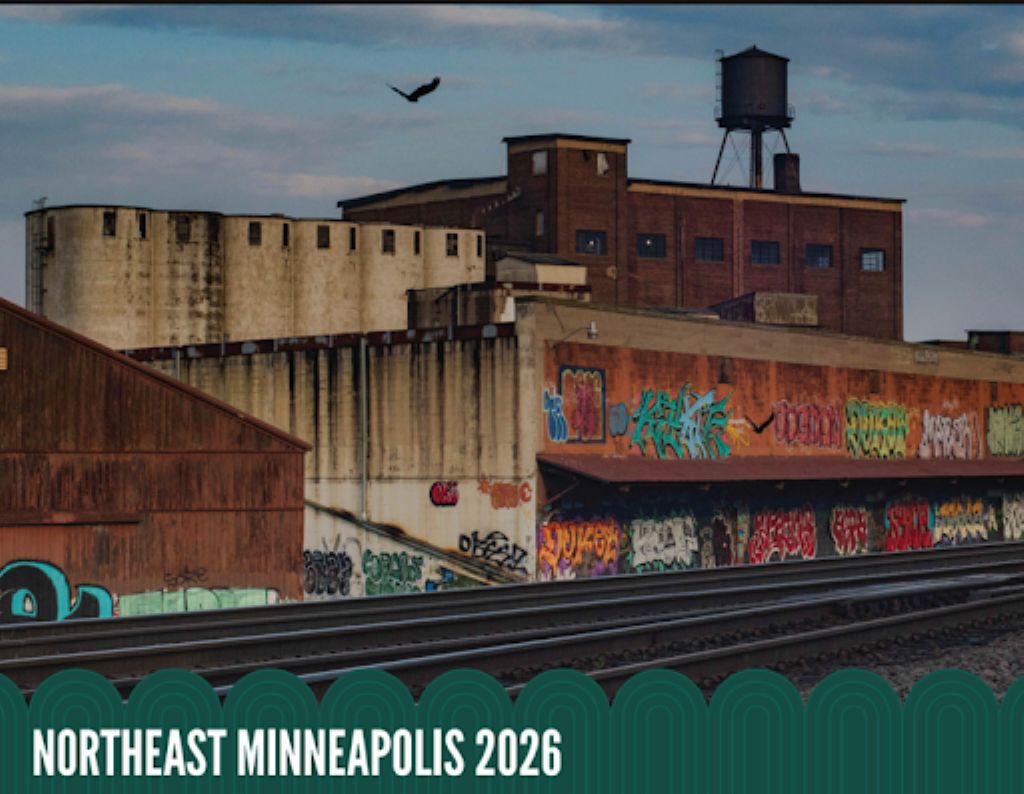 Old industrial buildings with graffiti-covered walls sit alongside railroad tracks under a cloudy sky, with the text NORTHEAST MINNEAPOLIS 2026 at the bottom.