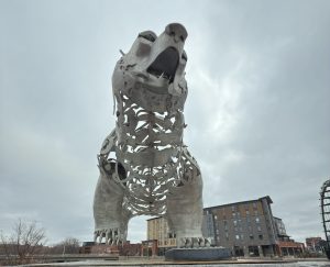 A towering, open-work metal sculpture of a bear standing on its hind legs against a cloudy sky.