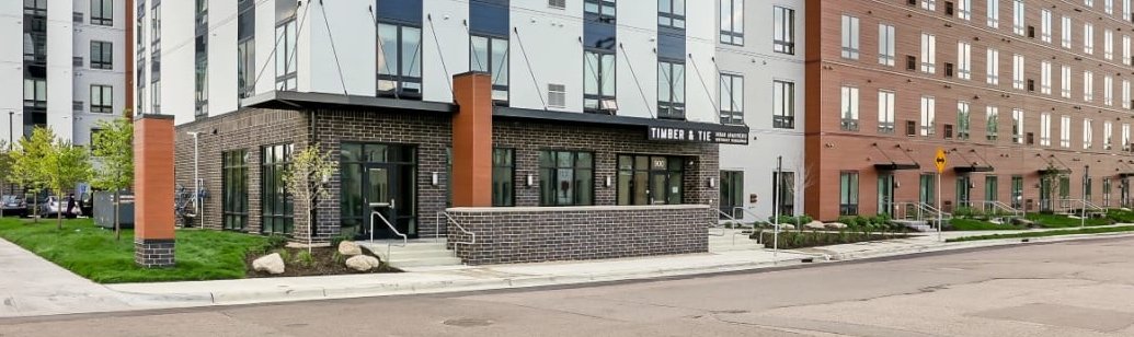 Exterior view of the Timber & Tie apartment building with a brick and light-colored facade.